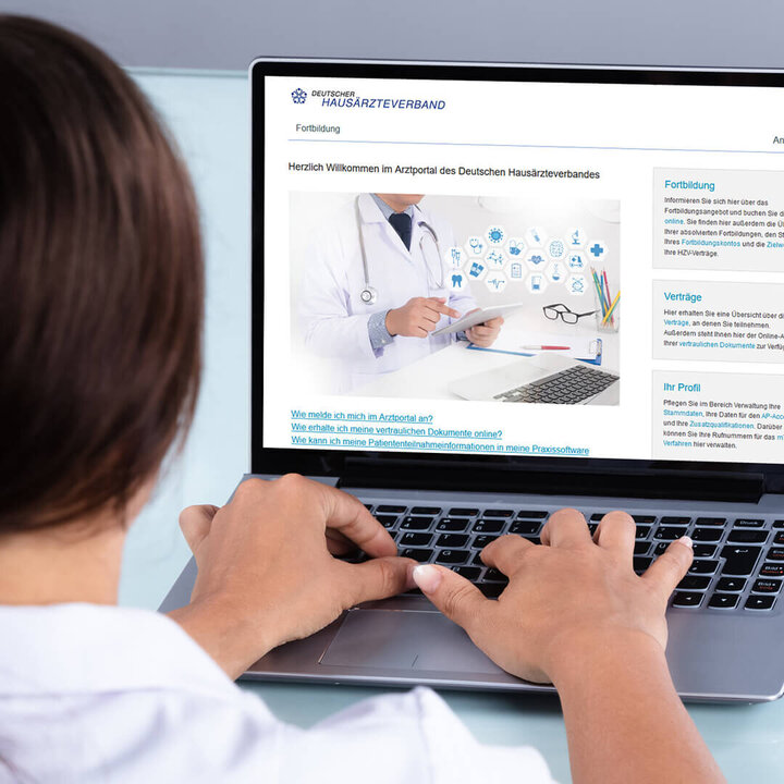 Eine Ärztin tippt auf einer Tastatur und sitzt vor einem Desktop, der das Ärzteportal zeigt.