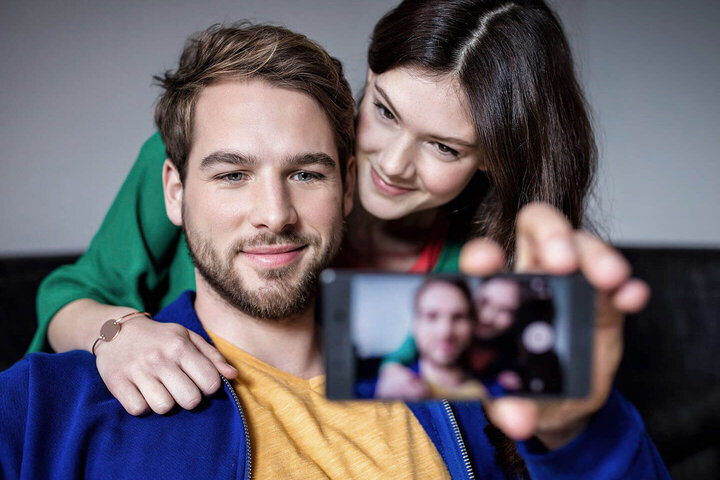 Mann und Frau machen ein gemeinsames Selfie mit einem Mobiltelefon.