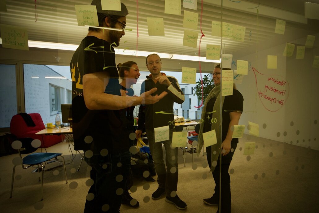 Hackathon-Teilnehmer Brainstormen mit Klebezetteln an der Wand